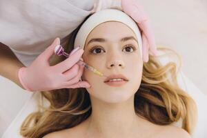 Cosmetologist administering a botox injection into a woman's lips while she relaxes in a wellness center, enhancing her beauty and rejuvenation photo
