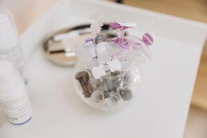 Used botox vials and vacuum cups are placed in a glass container on a white table in a cosmetology clinic photo