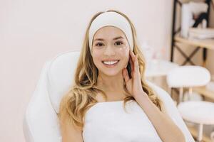 Beautician spreading moisturizing cream on client's face during professional skincare treatment at spa photo