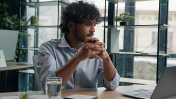 Thoughtful man Arabian Indian businessman employer manager working with laptop pensive thinking pondering idea solving business problem solution creative computer work in office consider think doubt photo
