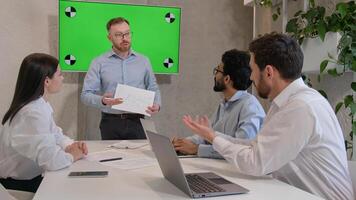 Male leader speaker coach talking to team multiracial men listen to CEO businessman teaching employees showing business presentation at group conference pointing at green interactive board chroma key photo