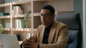 African American businessman ethnic puzzled man employer manager CEO entrepreneur working with laptop at office commerce work planning business startup solve issue think idea problem solution doubt photo