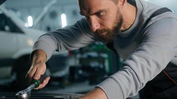 Caucasian mechanic in uniform repairing engine fixing motor inside open bonnet automobile professional auto service male vehicle engineer repairman man using wrench tool car maintenance in workshop photo