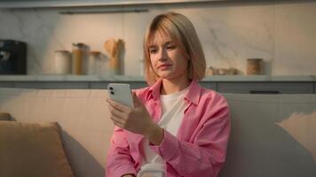 Caucasian woman at couch sofa typing chat message girl female lady influencer user using mobile phone browsing smartphone app social media internet online shopping at home chatting e-commerce addict photo
