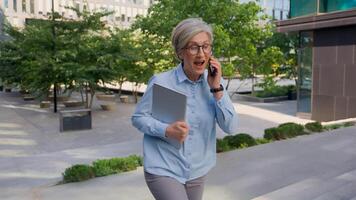 Caucasian mature 50s old woman businesswoman business employer walking up stairs going upward office building in city talking phone check time looking at wrist watch late rush hurry running lateness photo