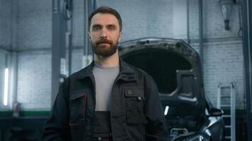 Portrait of smiling auto mechanic technical employee in work uniform looking camera at car repair service station happy male specialist Caucasian bearded man smiling concept of automobile maintenance photo