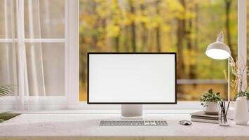A front view of a computer on a desk, set against a window overlooking a scenic autumn landscape. photo