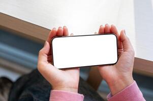 A close-up top view of a woman's hand holding a smartphone horizontally while watching a . photo