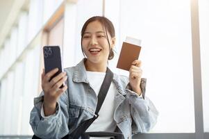 A cheerful Asian female passenger enjoys talking on a call while waiting for her flight. photo