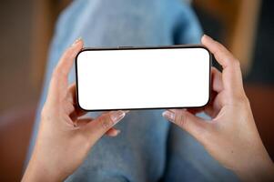 A close-up top view of a woman using a smartphone while sitting indoors, watching a . photo