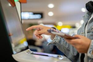A close-up image, A female passenger is checking in for her flight at an airport self-check-in kiosk photo