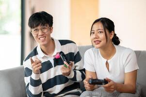Two cheerful Asian friends are enjoy playing a game on the sofa in the living room together. photo