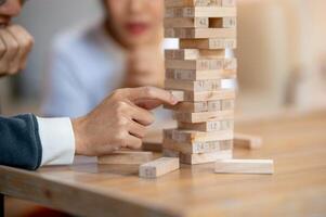 A close-up of a man's fingers carefully removing a wooden block while playing Jenga at home. photo