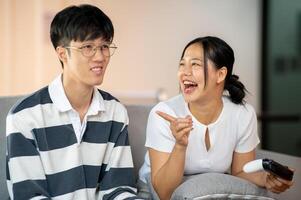 Two cheerful and joyful Asian friends are enjoy playing a game on the sofa together. photo