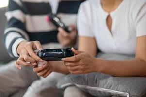 A close-up of two friends play a game with joysticks on the sofa. photo
