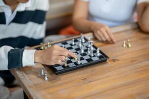A man playing chess with his friend, moving a piece on the board, enjoying a fun time together. photo