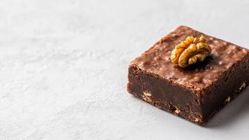 Delicious square of fudge topped with walnut on light background photo