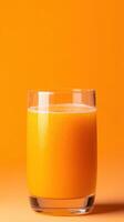 Fresh orange juice in clear glass against vibrant orange background photo