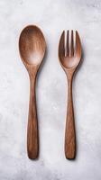 Neatly arranged wooden spoon and fork set on textured background photo