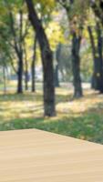Empty wood table with green tree at park bokeh blur vertical background copy space for display of product video