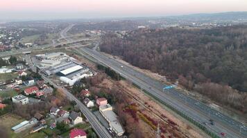 Aerial view of a highway surrounded by residential areas and forest in Krakow, Poland, Expansive highway network running through suburban neighborhoods and natural landscapes in Krakow video