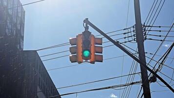 Traffic light with green signal hanging among cables on a bright sunny day, green traffic light surrounded by utility cables, with bright sunlight in the background video