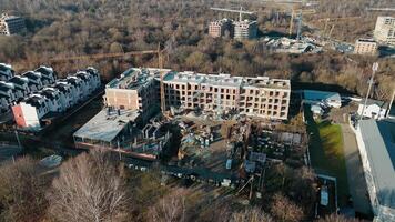 Aerial view of a residential construction site, showing a building under development and cranes in a wooded suburban area. video