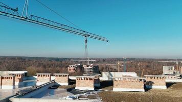 Construction site with cranes and partially built structures, surrounded by forest and clear blue sky. video