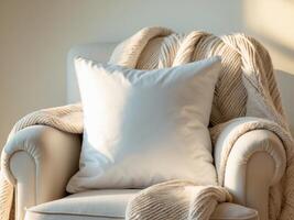 A plain white square throw pillow, placed on a cozy armchair with a textured blanket draped over it. photo