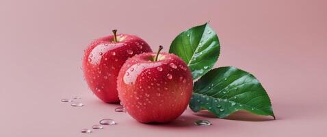Two red apples with water drops and green leaf on pink background. photo