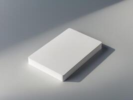 A white card is on a grey surface with a shadow of the card on the ground. photo