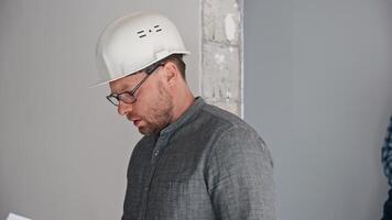 A construction engineer and a foreman inspect the construction site and discuss the progress of construction work. The men consult the drawings. Investment project video