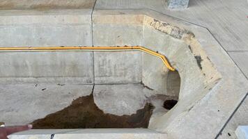 Concrete Water Feature A close-up view of a concrete water feature with a yellow pipe. The water feature is rectangular and has a curved edge. photo