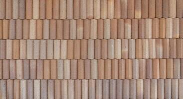 A textured brick wall with cylindrical clay bricks arranged in a horizontal pattern, creating a rustic and earthy surface. photo
