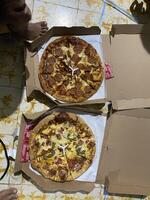 two pizzas in boxes on a table photo