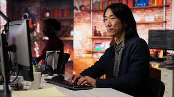 Portrait of smiling senior engineer coding advanced AI algorithm in startup office, refining machine learning models. Cheerful man using coding platform in Silicon Valley workplace, camera B video