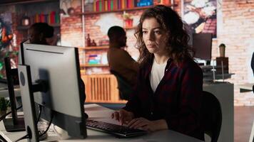 Portrait of happy woman working in AI tech agency providing custom software development services. Jolly IT staff member using machine learning to streamline coding process in startup office, camera A video