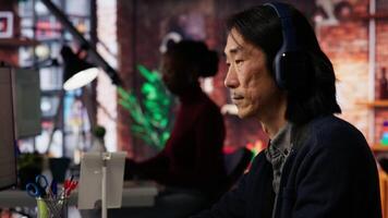 AI startup office chief technology officer listening music while coding application. Senior programmer wearing headphones while working in artificial intelligence software development agency, camera B video