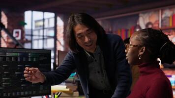 Artificial intelligence startup company manager overseeing programmer building application. Asian team leader assisting worker in AI software development agency, offering advice, camera B video
