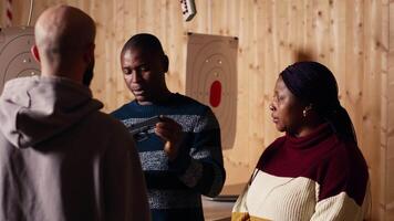 Shooting range safety officer ensuring clients are following regulations and operating firearms safely. African american firing range gallery worker giving instructions to customers, camera B video