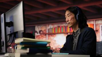 Senior admin coding advanced AI algorithm in startup office, refining machine learning models to enhance automation, wearing headphones. CTO manager listening music and coding, camera B video