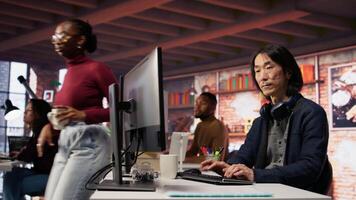 AI startup senior programmer overseeing deep learning application, thinking how to improve software. Asian artificial intelligence tech venture engineer using PC to fix code bugs, camera B video
