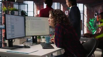 Happy employee using programming languages on PC in IT startup office to build applications. Cheerful IT expert using computer in software development agency to code, camera A video