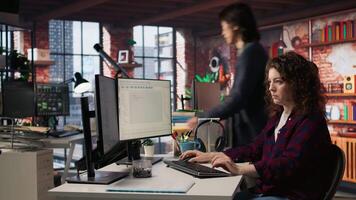 Smiling woman using programming languages on PC in IT startup office to build applications. Upbeat programmer using computer in software development agency to code, camera A video