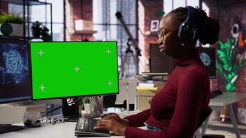 African american woman uses mockup PC in AI tech company providing software development services. Startup IT expert uses AI to streamline coding process on green screen PC video