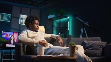 Young black person overseeing schedule and planning activities at his home, working on time management with online tools. Male adult utilizing a calendar on pc and checking the planner. Camera B. video