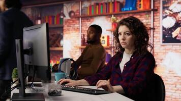 Smiling woman using programming languages on PC in IT startup office to build applications. Upbeat programmer using computer in software development agency to code, camera B video