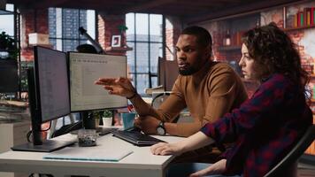 IT employees in startup office working at computer desks, testing and deploying programs and systems. Programmer and developer checking code on desktop PCs, solving tasks in workspace, camera A video