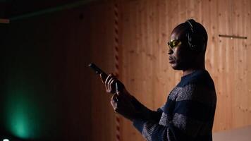 Person wearing safety goggles loading pistol bullets magazine during firearm practice session at shooting range. African american man reloading gun, learning self defense, pointing weapon, camera A video