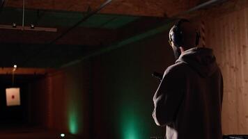 person bär skyddande redskap läser in tidskrift i pistol under skjutvapen öva session på skytte räckvidd. pistol entusiast ladda om handeldvapen, inlärning själv försvar, pekande vapen, kamera en video